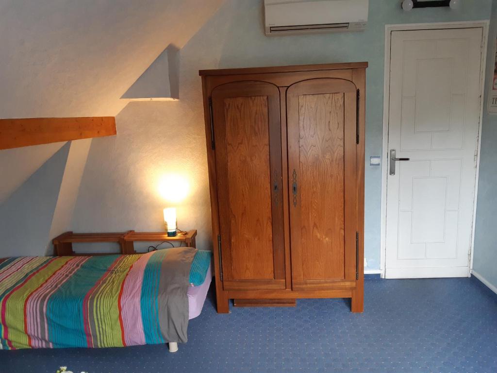 Schlafzimmer mit einem Bett und einem Holzschrank in der Unterkunft le petit chemin in Bougival
