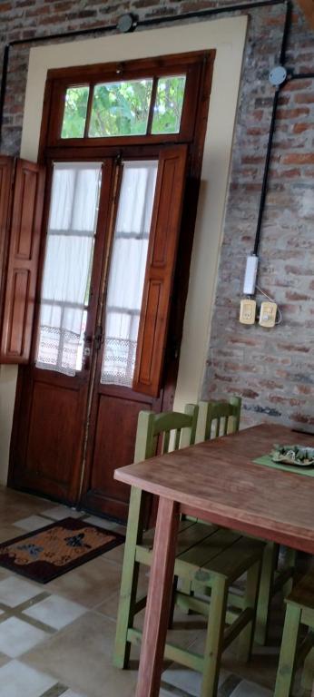 einen Holztisch und Stühle in einem Zimmer mit Tür in der Unterkunft Los tilos in San Antonio de Areco