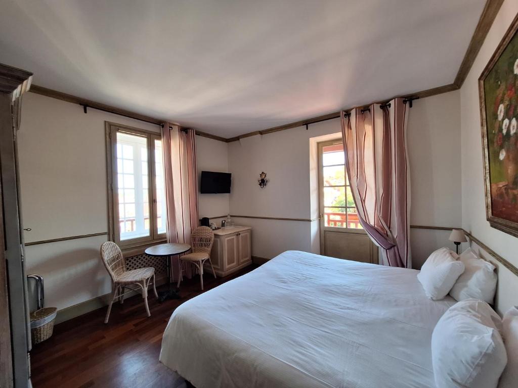 a bedroom with a bed and a desk and two windows at Hotel Villa Catarie in Guéthary