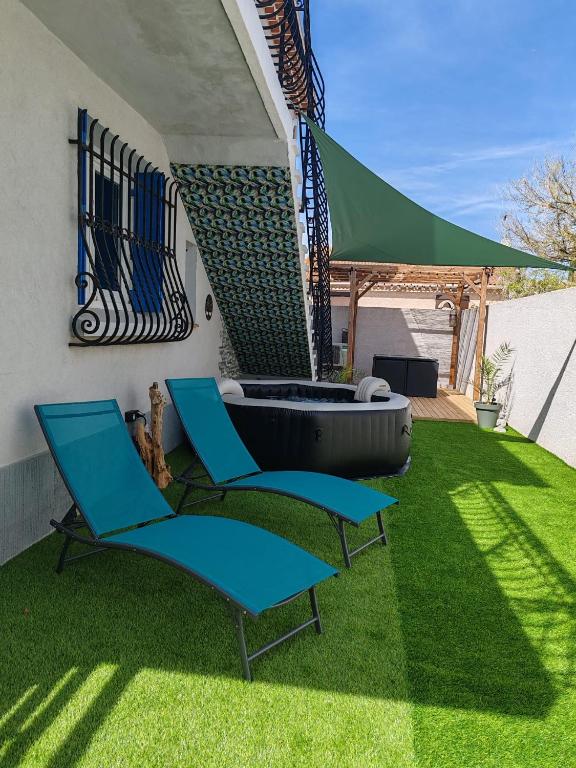 - deux chaises et une baignoire dans une cour avec de l'herbe dans l'établissement Superbe appartement pour deux avec jacuzzi, à Vias