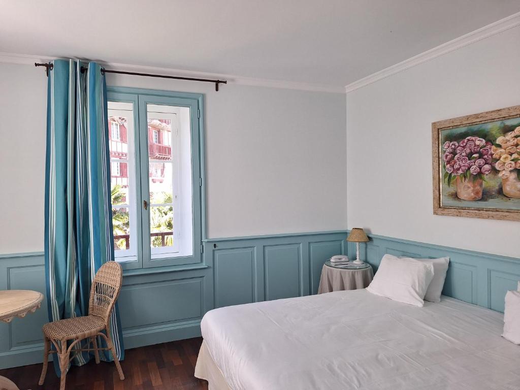 a bedroom with a bed and a table and a window at Hotel Villa Catarie in Guéthary