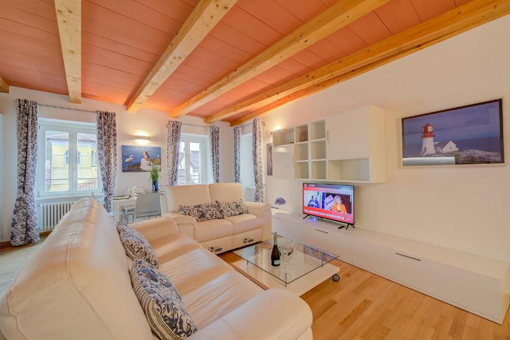 uma sala de estar com um sofá branco e uma televisão em Concordia Apartment Laveno - Happy Rentals em Laveno