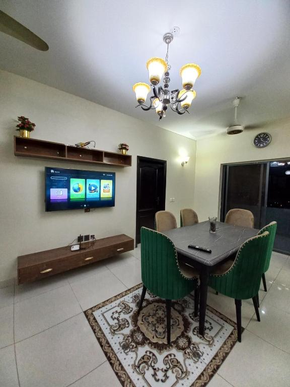 a dining room with a table and chairs and a tv at Modern Luxury Guest Apartment With All Facilities in Karachi