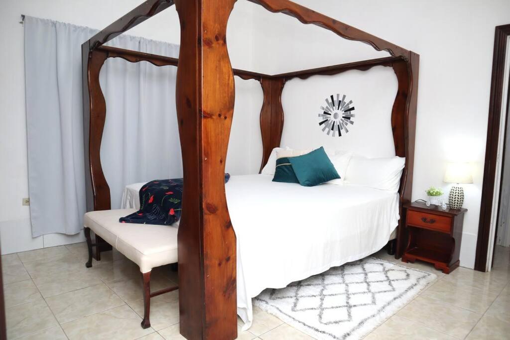 1 dormitorio con cama de madera con dosel y silla en Mandeville Chateau, en Mandeville