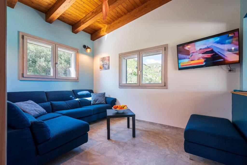 un salon avec un canapé bleu et une télévision à écran plat dans l'établissement Villa Maguetta with private pool in Scopello, à Scopello