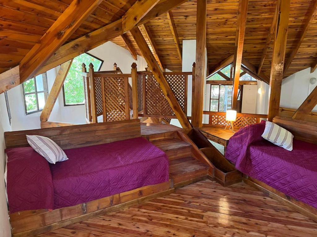 two beds in a room with wooden floors and wooden ceilings at Aljabas in San Martín de los Andes