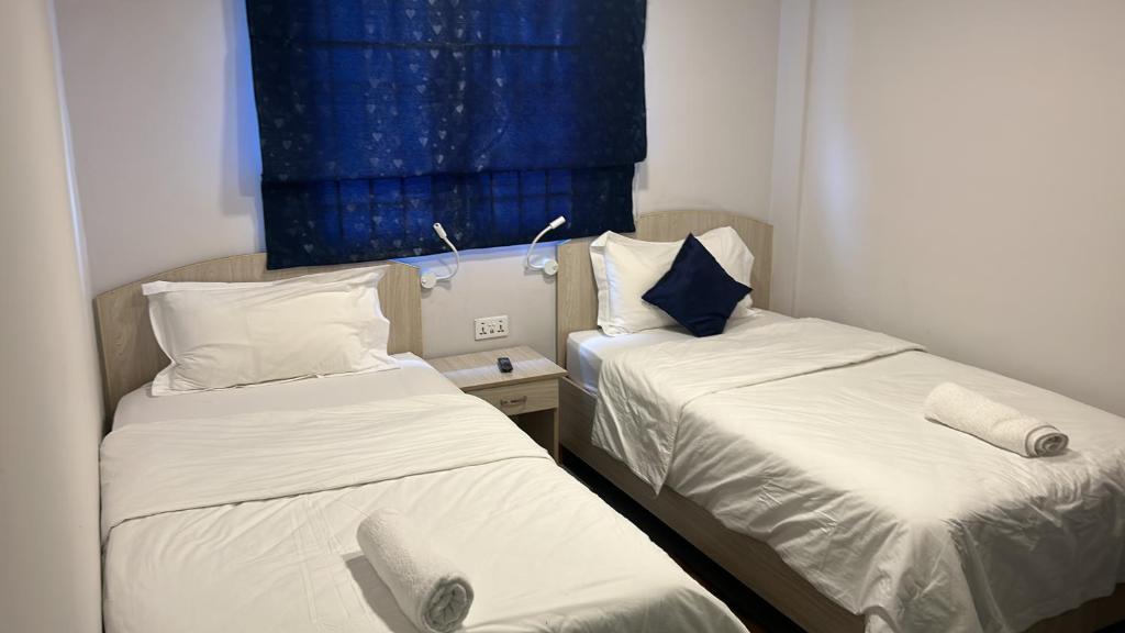 2 łóżka pojedyncze w pokoju z oknem w obiekcie Le palbot w mieście Quatre Bornes
