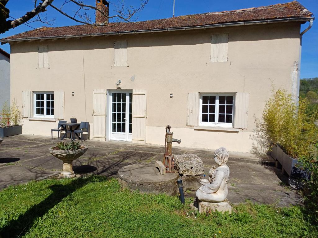 uma casa branca com uma estátua em frente em Gîte de la rivière em Pineuilh