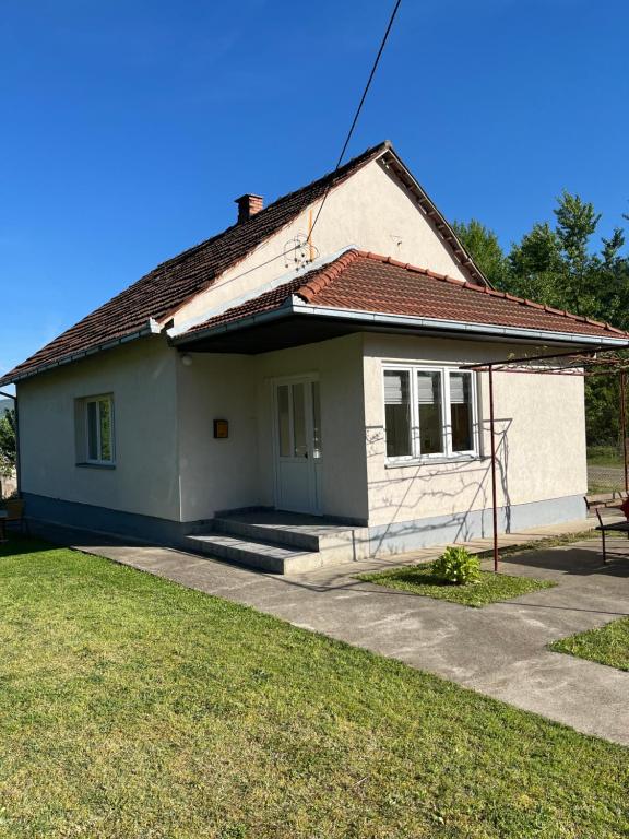 una pequeña casa blanca con un patio de césped en Vikendica Lazić, en Ljubovija