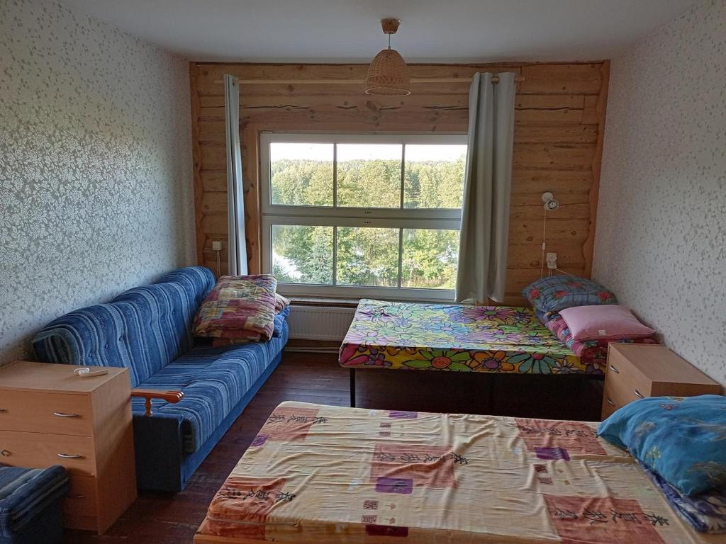 Habitación con 2 camas, sofá y ventana en Neciunu sodyba, en Bijūnai