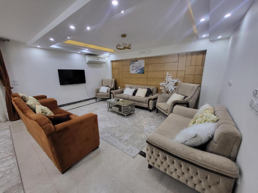 uma sala de estar com sofás e uma televisão de ecrã plano em شقه فندقيه بالدقي no Cairo