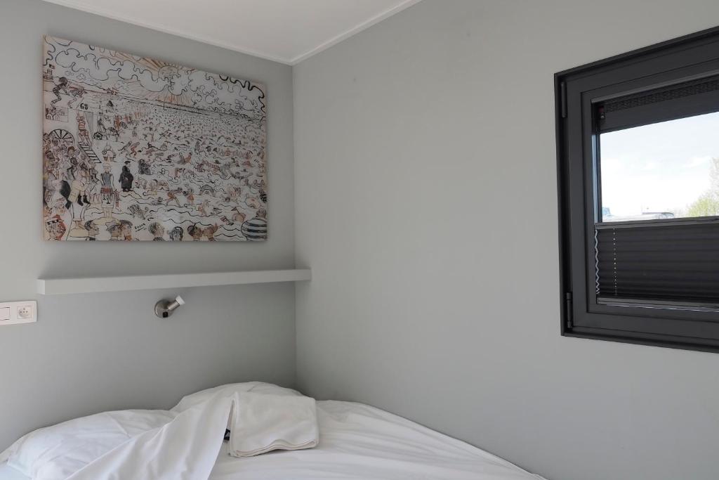 Un dormitorio con una pintura en la pared y una cama en Houseboat Tiny Griffin, en Nieuwpoort
