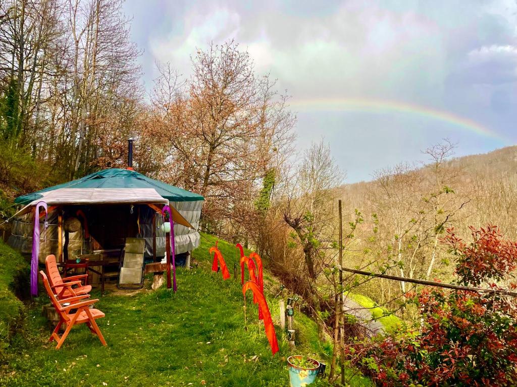 een tent met stoelen en een regenboog op de achtergrond bij Les songes du chêne in Augirein