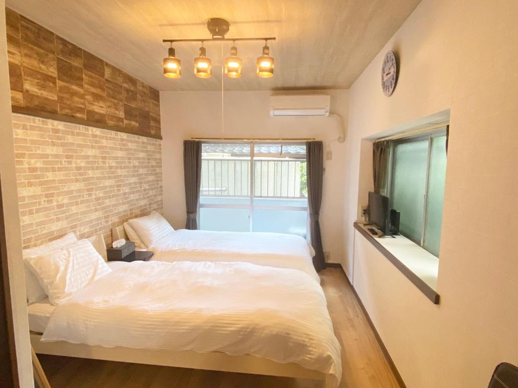 a bedroom with two beds and a brick wall at Rapport Kukomae 207 in Fukuoka