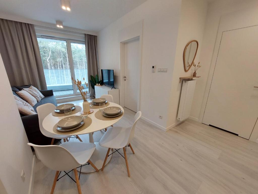 a dining room with a table and chairs in a living room at Harmony Pearl Apart in Rogowo