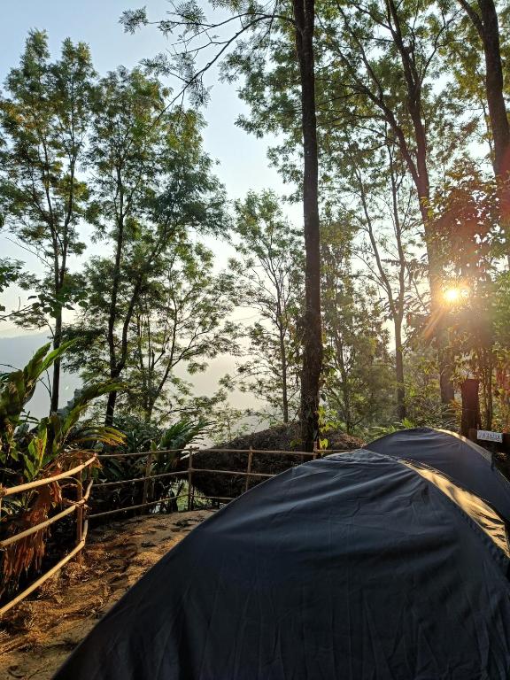 a tent with the sun shining through the trees at Evara by The Offbeat Crew in Idukki