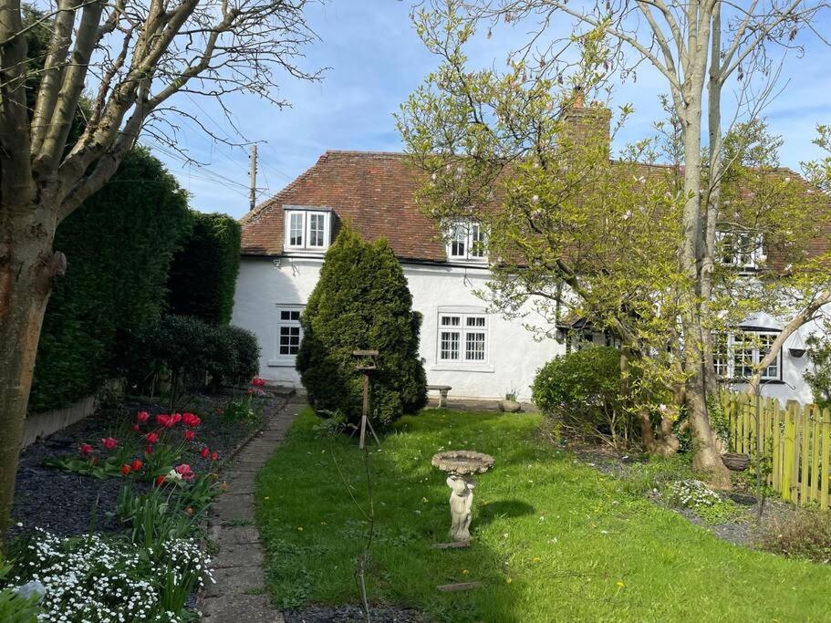 een wit huis met een tuin met een standbeeld in de tuin bij Cosy Daffodil Cottage in Eythorne