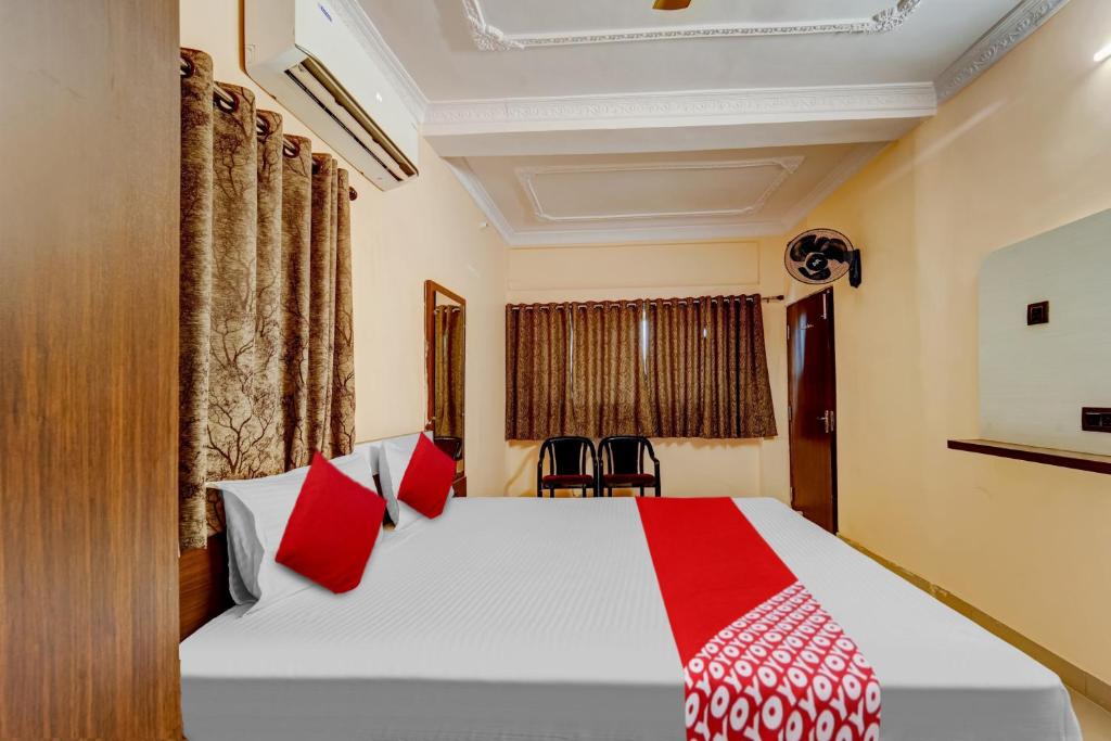 1 dormitorio con 1 cama blanca grande con almohadas rojas en OYO Flagship Relax Inn, en Dhanbād