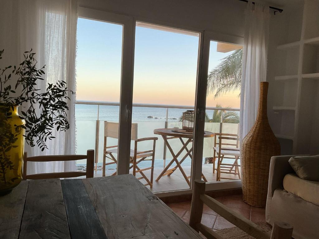 a living room with a table and a view of the ocean at Attico fronte mare Espardell19 Es Pujols in Es Pujols
