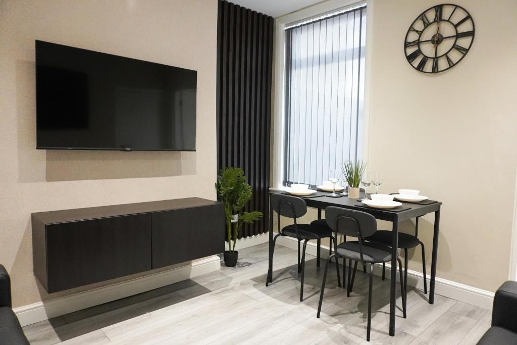 a dining room with a table and chairs and a television at Brand New Anfield Home Free Parking, 2 mins from LFC, 15 Mins City Centre in Liverpool