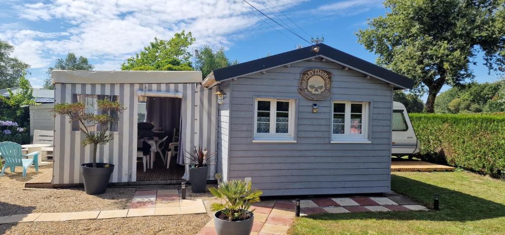 un petit hangar gris avec une horloge sur la porte dans l'établissement Chalet et caravane sur terrain privé , mer à pied, à Pénestin