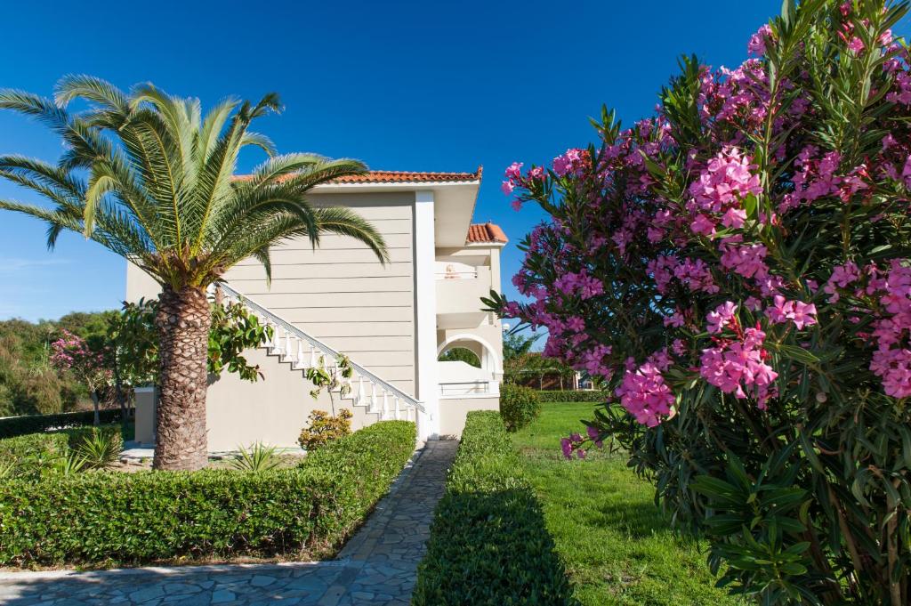 a house with a palm tree and pink flowers at Kalamaki Beach Hotel, Zakynthos Island in Kalamaki