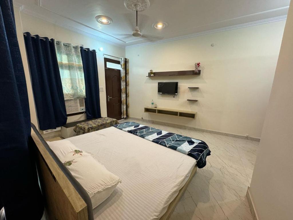 Cette chambre comprend un lit et une télévision. dans l'établissement Ved Vatika Homestay, à Faizābād