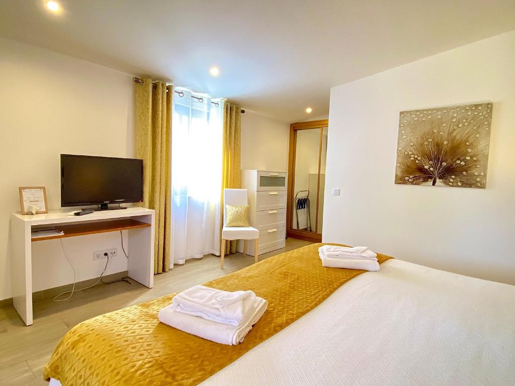 a bedroom with a bed and a desk with a television at Quinta das Andorinhas in Carvoeiro