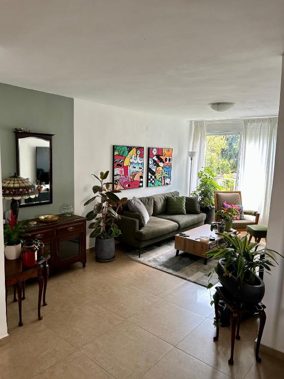 uma sala de estar com um sofá e algumas plantas em A private room in a modern apartment near the Belinson/Schneider hospital and the Red Line to Tel Aviv em Petaẖ Tiqwa
