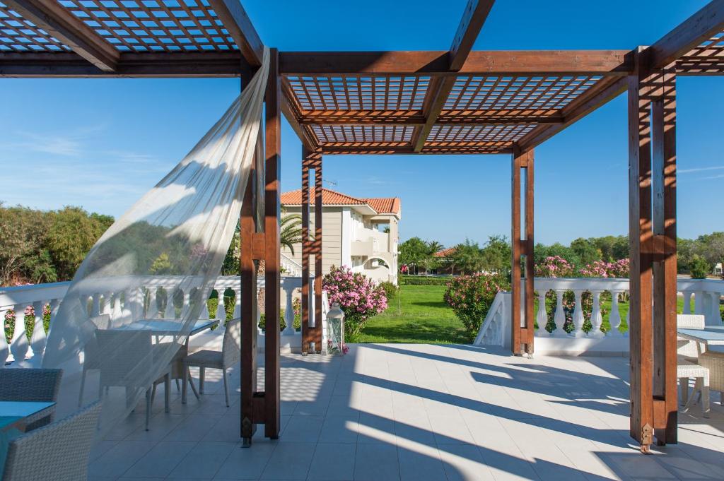 a pergola with tables and chairs on a patio at Kalamaki Beach Hotel, Zakynthos Island in Kalamaki