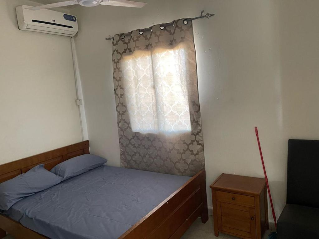 ein kleines Schlafzimmer mit einem Bett und einem Fenster in der Unterkunft Samba Tako Plaza Home Suites in Sukuta