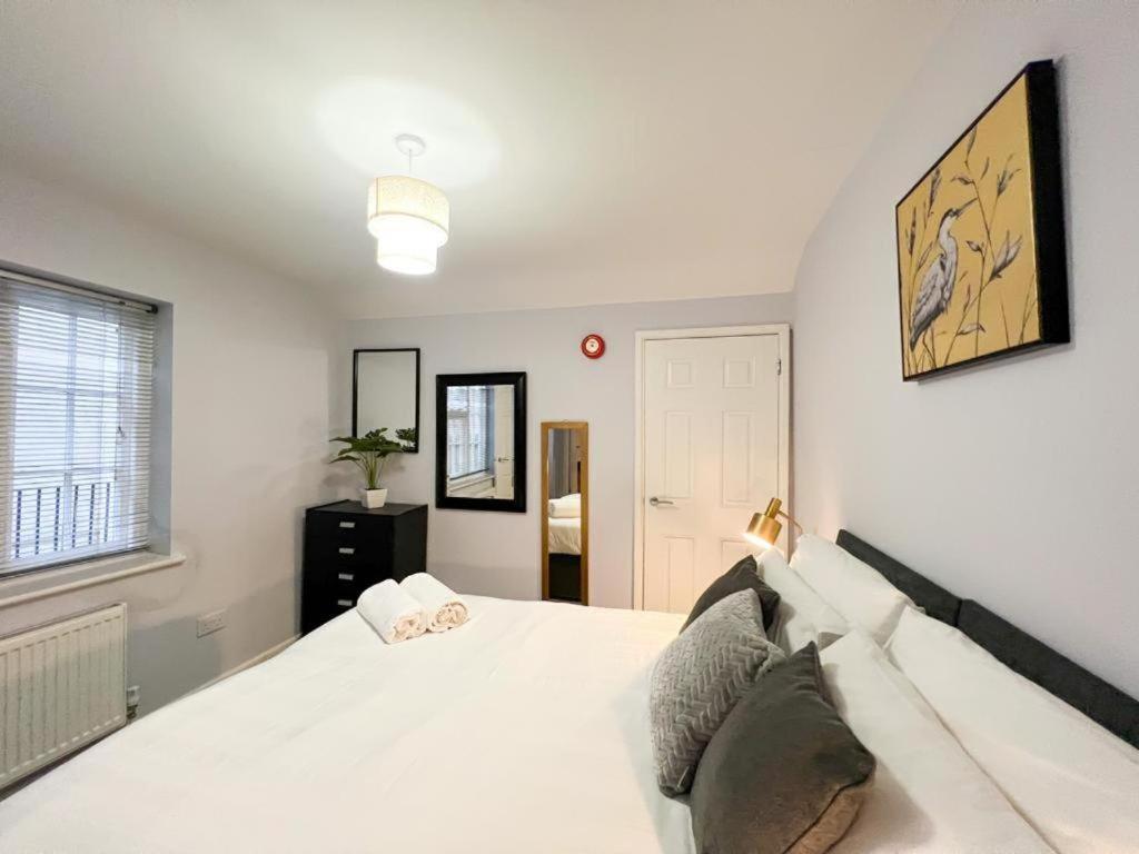 a bedroom with a white bed and a window at Suitely Stays Patio Apartment in Cheltenham
