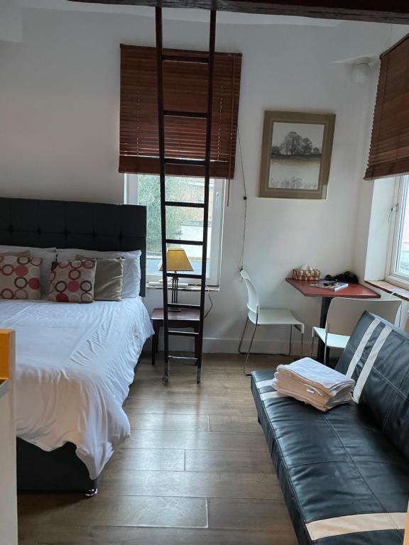 a bedroom with a bed and a couch and a ladder at Unique London Apartment, ideal for Long Stays in Finchley