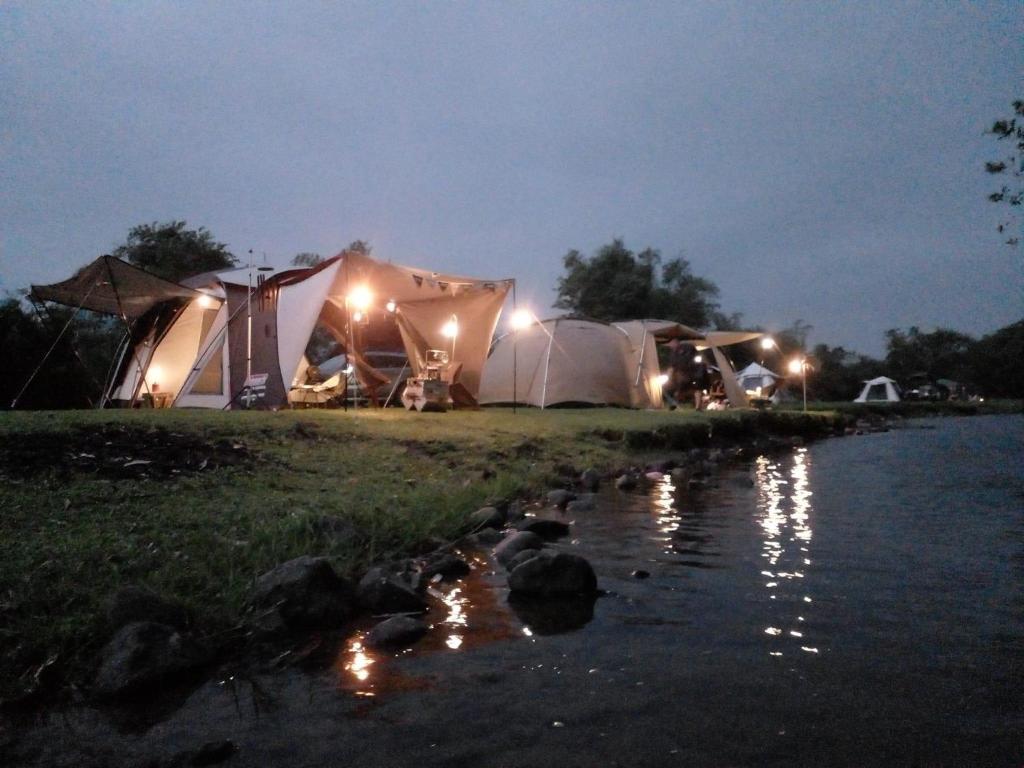 una fila di tende di notte accanto a un fiume di Camping Suối Cái a Kim Bôi