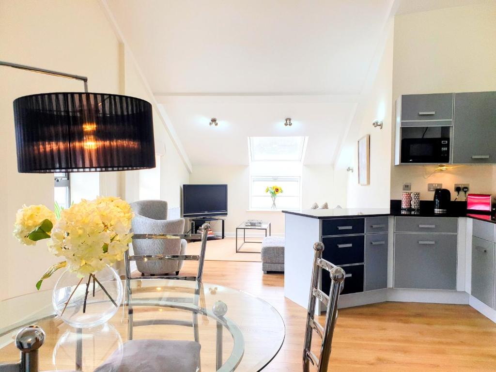 a living room with a glass table and a kitchen at THE PENTHOUSE AT REGENT HOUSE Light and airy top floor with lift access 1 bedroom en-suite luxury apartment ULTRA CENTRAL LOCATION in Harrogate