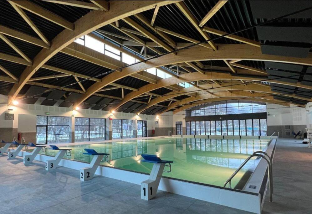 a large swimming pool with a green floor in a building at Charmant Logement de plein pied avec piscine 2* in Loudenvielle