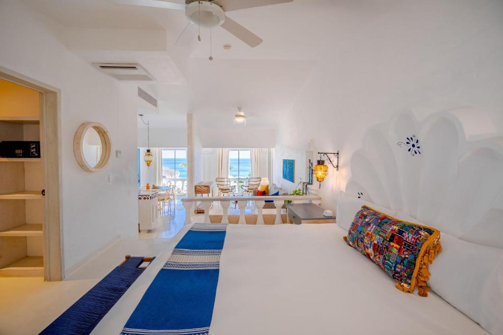 a white bedroom with a bed and a living room at Mar del Cabo By Velas Resorts in San José del Cabo