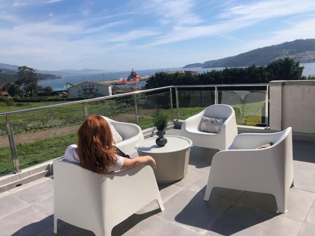 een vrouw in witte stoelen op een balkon bij A Neida Casa con terraza con vistas al mar in Cee