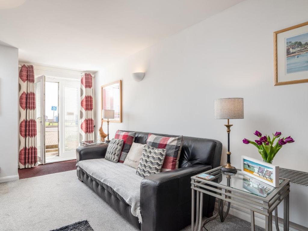 a living room with a black leather couch and a table at 14 Belvedere Court in Paignton