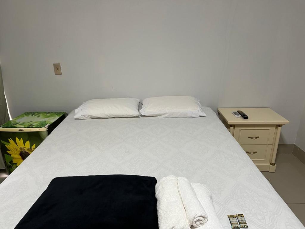 a bed with white sheets and towels on it at Suíte completa no centro de Sinop in Sinop