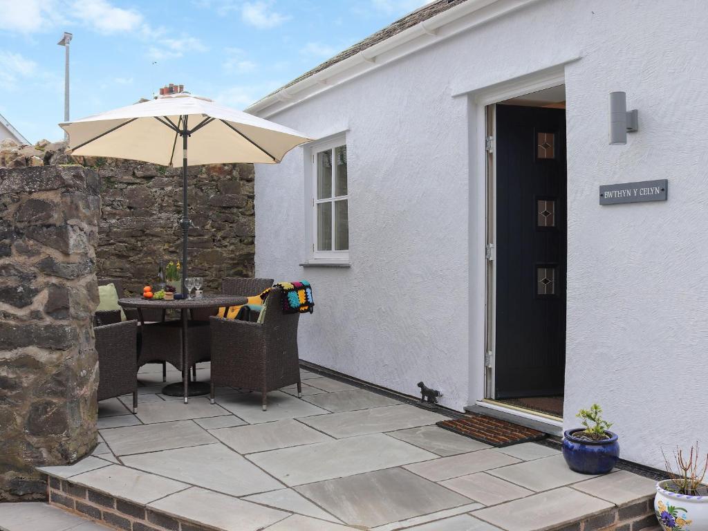 une terrasse avec une table et un parasol dans l'établissement Bwthyn Y Celyn, à Conwy