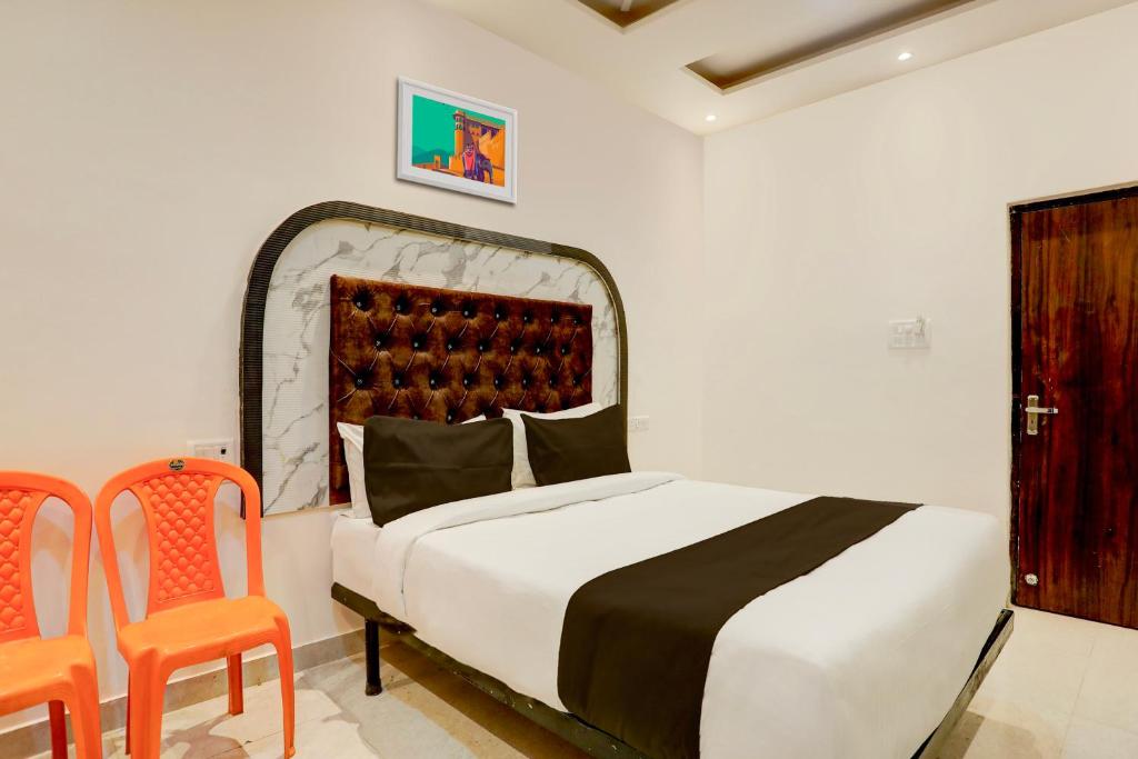 バラナシにあるSuper OYO Flagship SHIVA VALLEY HOTELのベッドルーム1室(ベッド1台、オレンジ色の椅子2脚付)