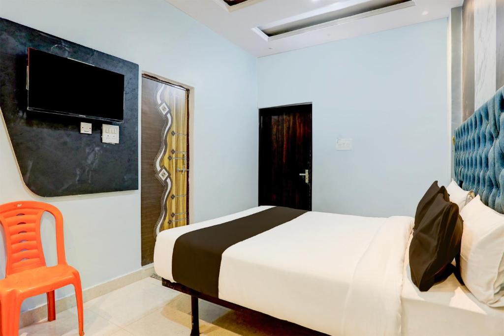 a bedroom with a bed and a chair and a tv at OYO Flagship SHIVA VALLEY HOTEL in Varanasi