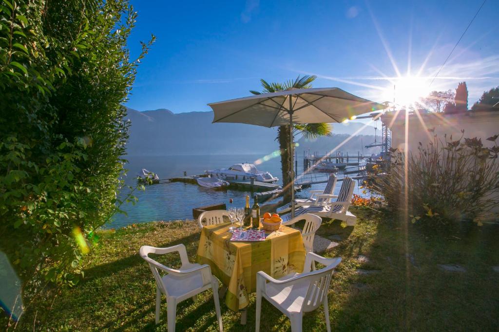 una mesa con sillas y una sombrilla junto al agua en Casetta al Lago, en Mezzegra