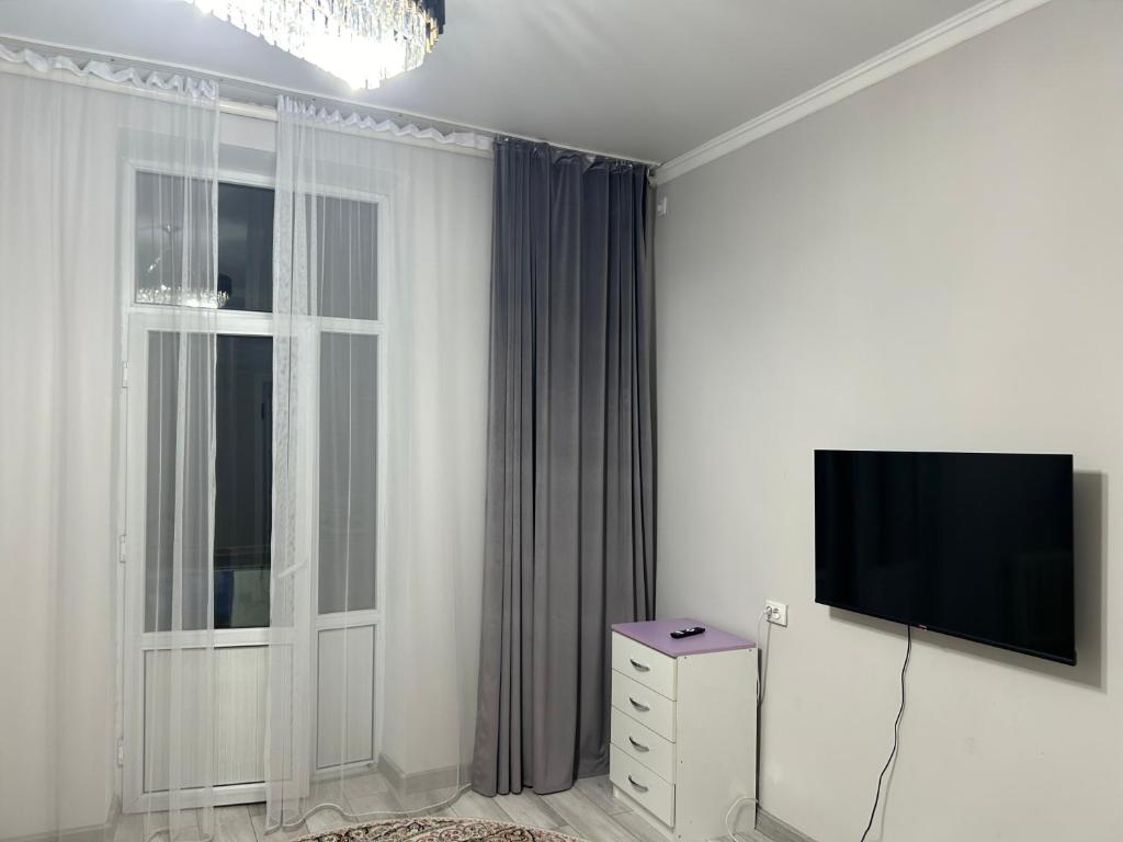 ein Wohnzimmer mit einem TV und einem Fenster in der Unterkunft GuKu Fly Apart in Turksib