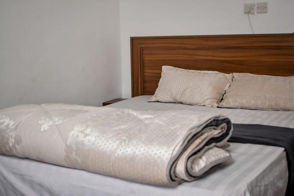 Una cama con cabecero de madera y una toalla. en Mella homes limuru, en Kiambu