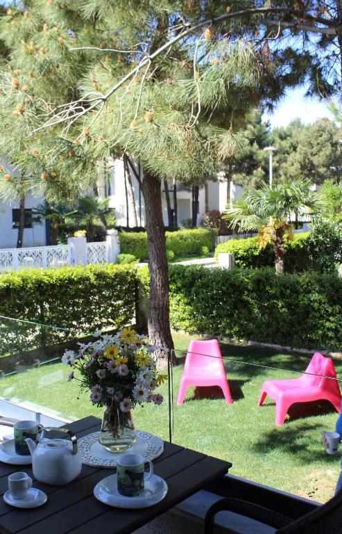 a table with a vase of flowers and pink chairs at Vala Mar Apartament in Draç