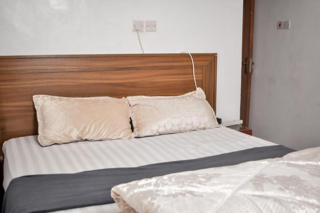 a bed with a wooden head board and two pillows at Mella homes limuru in Limuru