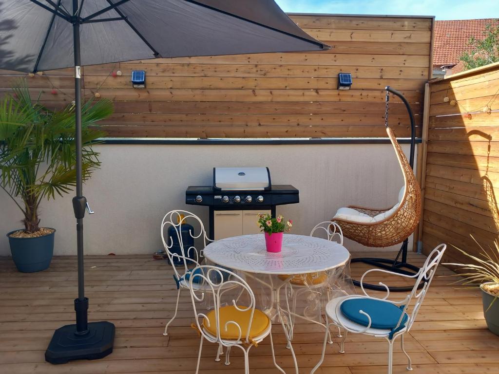 een patio met een tafel en stoelen en een grill bij Maison de charme L'hirondelle en Auvergne in Champs