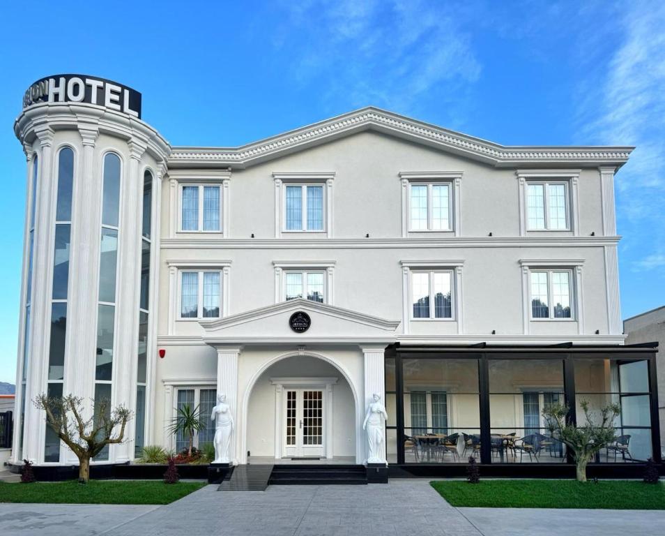 een groot wit gebouw met een hotelbord erop bij Reign Hotel in Vorë